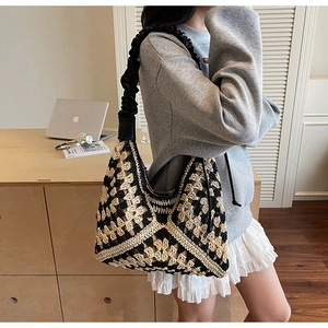 Detail of knit crochet tote bag with geometric pattern and black leather pleated shoulder strap
