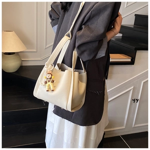 Dettaglio della borsa a secchiello in pelle beige con motivo litchi e ciondolo a forma di orso