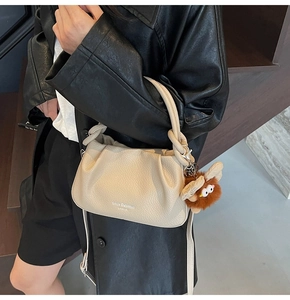 Detail view of cream pleated crossbody bag with plush bird charm and leather texture