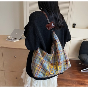 Détail du sac fourre-tout en toile à carreaux bleu et jaune avec broderie et pendentif