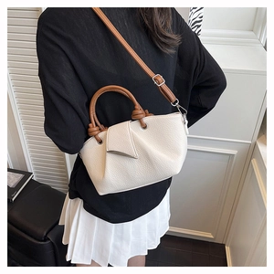 Detail of lychee pattern leather shoulder bag featuring hand-knotted handle and brown strap