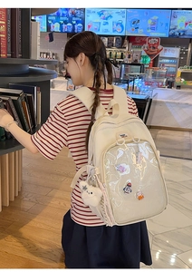 Detail of cream canvas itabag backpack with clear PVC window and plush bear charm