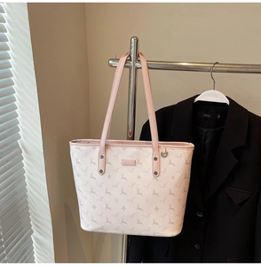 Detail view of pink tote bag with deer print and metallic brand plaque on suit display