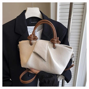 Detail of beige lychee grain leather bag with brown knotted handle and silver hardware