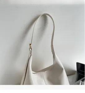 Close-up of beige leather tote bag featuring adjustable shoulder strap and gold hardware
