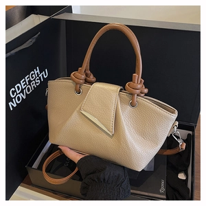 Detail of beige pleated handbag with brown knotted handle and metal buckle in gift setting