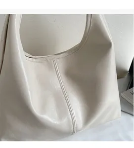 Large beige leather bucket bag shown in a cozy home office setting with a laptop
