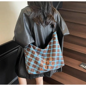 Détail du sac cabas à carreaux bleu et marron avec texte Noro Noro orange imprimé dessus