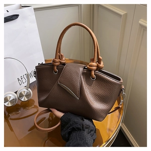 Close-up of deep brown lychee grain leather bag with crescent metal buckle and ring handles