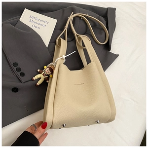 Dettaglio della borsa a secchiello in pelle beige con logo FASHION e ciondolo