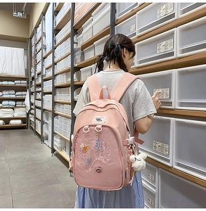 Pink school backpack featuring a transparent front pocket and cute plush pendant