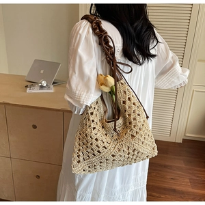 Detail of hollow crochet geometric pattern straw tote bag with brown pleated leather strap