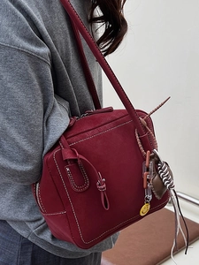 Minimalist deep red tote bag with contrast white stitching and decorative charms for women