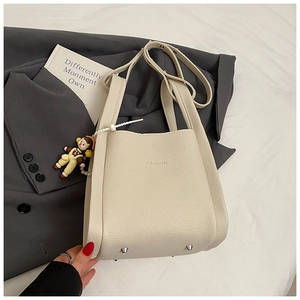 Dettaglio borsa a secchiello in pelle bianco crema con borchie e ciondolo moda