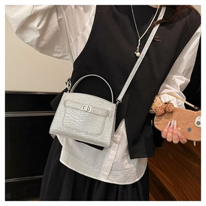 Detail of silver wavy texture handbag with metallic rotating lock and slender strap