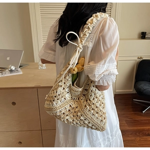 Detail of straw tote bag featuring white ruched shoulder strap and woven texture