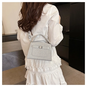 Silver sequin handbag with metal clasp and shoulder strap shown with elegant white lace dress