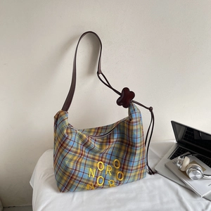 Détail du sac cabas en toile à carreaux classiques avec broderie jaune et bandoulière en cuir