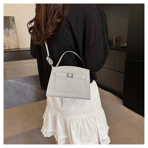 Detail of silver sequined handbag with metal twist lock and slim shoulder strap