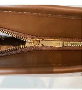 Dettaglio di una borsa tote in pelle marrone con cerniera in metallo dorato e scorrimento