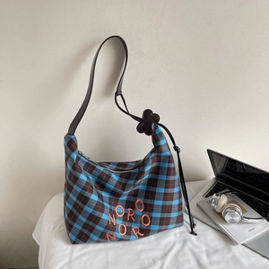 Détail du sac cabas à carreaux bleu et marron avec broderie NORO et breloque fleur