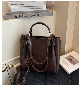 Detailed close-up of dark brown tote bag showing leather texture and gold hardware