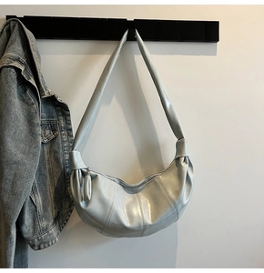 Detail of light blue crescent bag showing glossy faux leather texture and pleated stitching