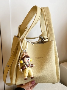 Borsa a secchiello in pelle giallo pallido con trama litchi e ciondolo alla moda