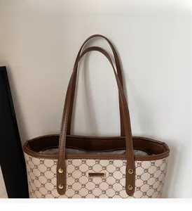 Dettaglio borsa tote in tela con manici in pelle rinforzata e motivo monogramma vintage