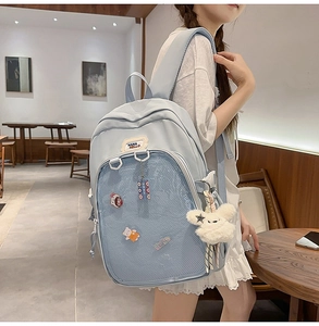 Detail view of light blue student backpack with transparent front mesh pocket and plush bunny charm