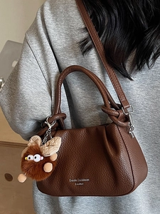 Fashionable dark brown leather crossbody bag with pleated texture and plush pendant accessory
