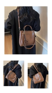 Detail of vintage brown leather bucket bag with metal handle and woven charm