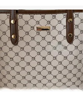 Dettaglio ravvicinato del tessuto beige della borsa tote con motivo monogram e manico
