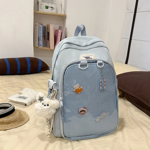 Detail of light blue school backpack with transparent mesh pocket and plush dog charm