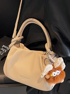 Chic beige ruched crossbody bag with textured leather and cute plush monster charm