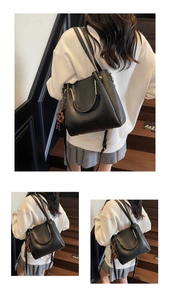 Detail of black PU leather bag with metal ring handle and fashion knot charm accessory