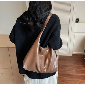 Brown leather large hobo shoulder bag shown on model in a minimalist home setting
