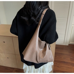 Brown glossy leather tote bag shown with an outfit to highlight its large capacity and texture