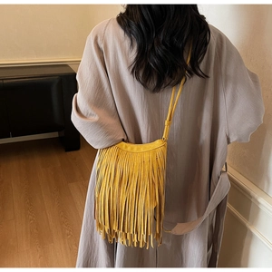 Close-up of yellow faux suede crossbody bag featuring long fringes and a bohemian tassel style