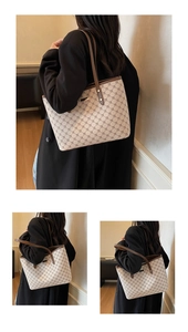 Dettaglio di una borsa tote beige monogram con manici in pelle marrone e metallo