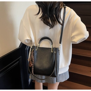 Fashionable black leather crossbody bag featuring gold metal hardware and tassel detail