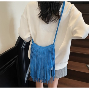 Detail of royal blue faux suede crossbody bag featuring long stylish fringe tassels