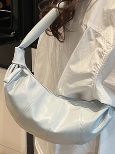 Minimalist light blue patent leather crescent crossbody bag with stylish knot details