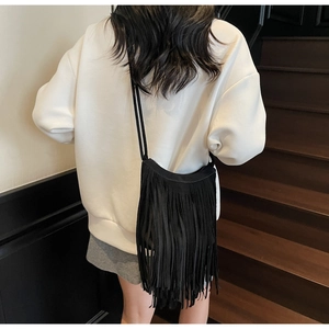 Back view of model wearing a black frosted suede crossbody bag with long fringes