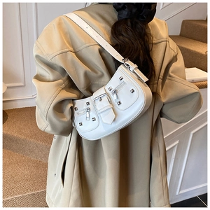 White vintage underarm bag with silver studs and buckles worn over a khaki trench coat