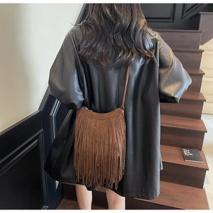 Brown suede crossbody bag with layered fringe detail shown on a leather jacket
