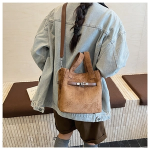 Detail view of a vintage brown suede bucket bag with leather strap and silver metal clasp