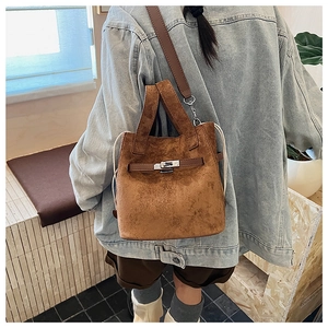 Close-up of brown suede bucket bag featuring silver turn-lock and leather shoulder strap