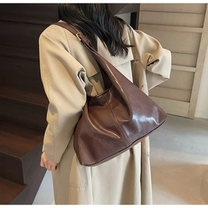 Detail of soft brown leather tote bag with gold buckle on an urban commuter shoulder bag