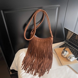 Detail view of brown suede fringe shoulder bag with long tassels in a vintage lifestyle setting